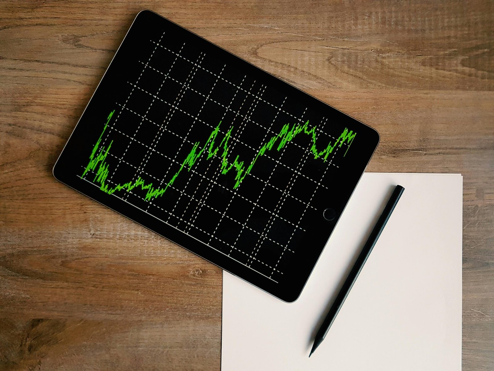 Mão apontando para um gráfico de ações em uma tela, simbolizando o investimento em ações para iniciantes.